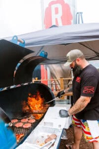 Man grilling burgers at Reformation Brewery outdoor event.